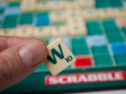 Une femme tient dans sa main la lettre W du scrabble
