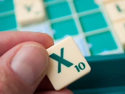 Une femme tient la lettre X au scrabble