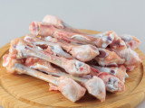 Un tas d'os de poulet sur une planche en bois sur un fond gris