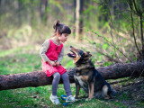 Une enfant assis à côté d'un chien dans un jardin