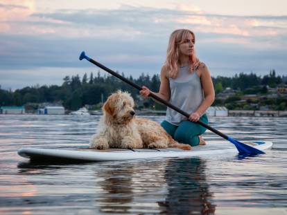 Une femme et son chien font du paddle sur un lac