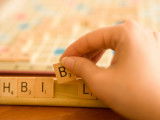 Une femme tient la lettre B du scrabble dans sa main