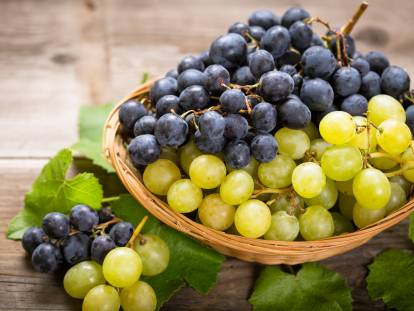 Un panier contenant des grappes de raisins noirs et blancs