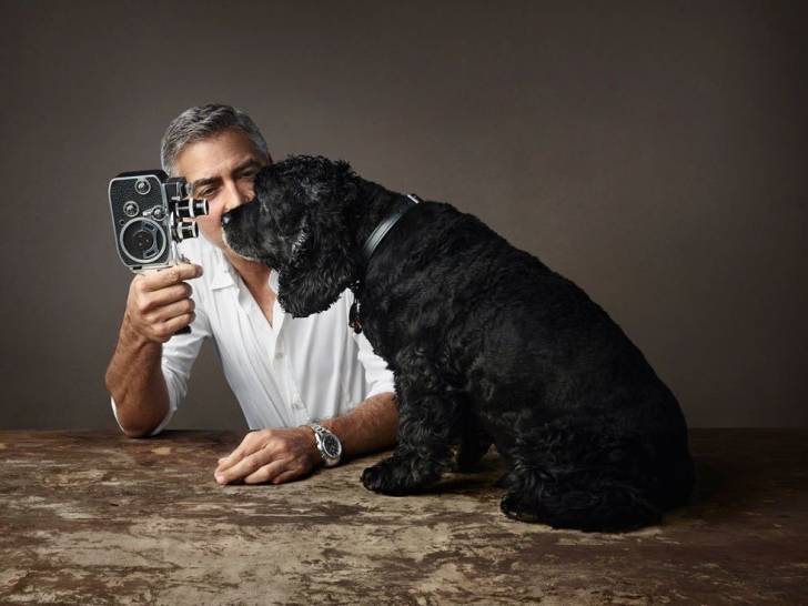 George Clooney et son chien Einstein assis sur une table en train de regarder une caméra ancienne