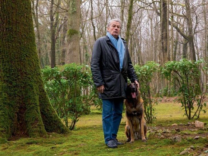 Alain Delon posant dans une forêt avec son chien Loubo à ses côtés
