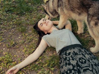 Un chien sentant une femme allongée par terre