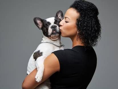 Femme qui embrasse son chien assis dans ses bras