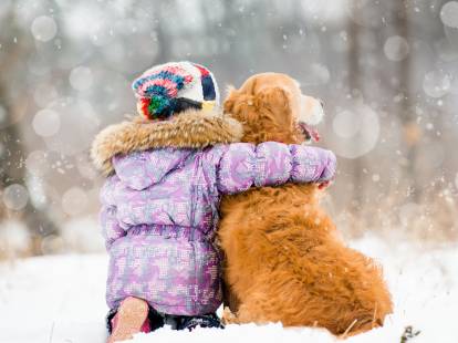 Un enfant et son chien assis dans la neige