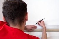 Un jeune homme prend des mesures sur un mur