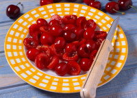 Des cerises dénoyautées avec un couteau dans une assiette