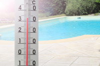Un thermomètre à côté d'une piscine ensoleillée