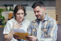 Un couple qui a l'air déçu en ouvrant une enveloppe