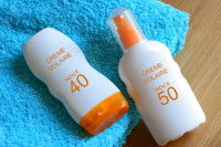 Deux flacons de crème solaire sur une serviette bleue