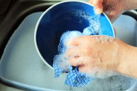 Un homme lave un bol avec une éponge dans le lavabo