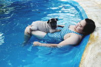 Une femme et son Carlin allongés dans une piscine