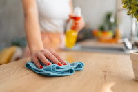 Une femme nettoie une table avec de l'alcool ménager