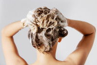 Une femme se lave les cheveux avec un shampoing