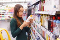Une femme choisit un shampoing dans un magasin