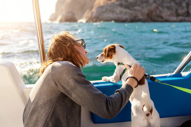 Une femme et son Jack Russel sur un bateau en mer