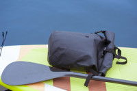 Un sac à dos étanche posé sur une planche de paddle