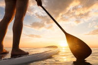 Une femme fait du paddle lors d'un coucher de soleil