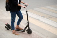 Une femme sur une trottinette devant un passage piéton