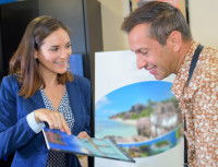 Une femme pr&eacute;sente une brochure sur des lieux de vacances &agrave; un homme
