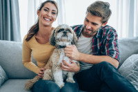 Un couple assis sur un canapé avec un chien sur les genoux