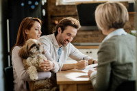 Un couple avec un chien signant des papiers auprès d'une personne