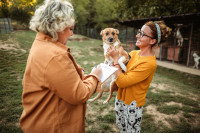 Une femme tenant un chien de refuge dans ses bras et une autre signant un papier