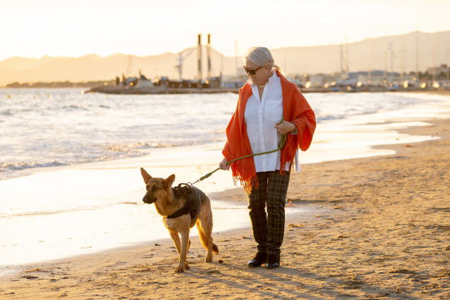 Une femme âgée sur une plage avec son Berger Allemand