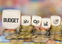 Des dés symbolisant le budget annuel posés sur un tas de pièces de monnaie