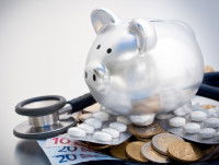 Une tirelire posée sur des médicaments et un stéthoscope