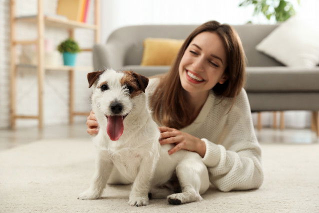 Une femme et son chien Jack Russel allongés sur le sol du salon