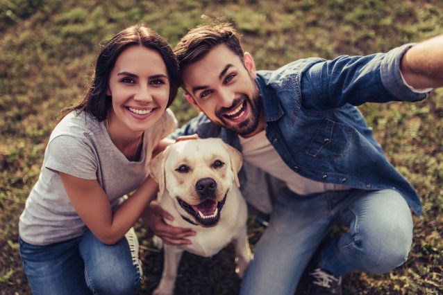 Un couple heureux fait un selfie avec son Labrador dans un parc