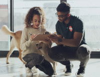 Une femme et un homme sont accroupis pour signer un document avec un chien entre eux