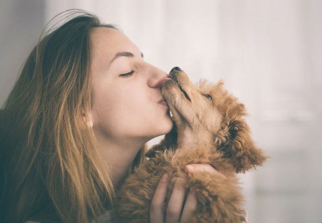 Une jeune femme fait un bisou à son Caniche