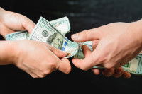 Duex mains s'échangent des billets de banque