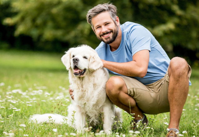 Un homme et son chien blanc heureux dans un jardin