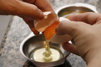 Un homme casse un oeuf en deux et sépare le blanc du jaune