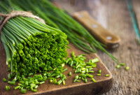 De la ciboulette sur une planche en bois