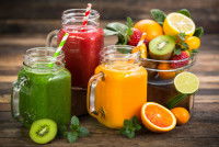 Des jus de fruits posés à côté d'une corbeille de fruits