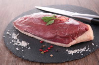 Un magret de canard cru sur une planche de cuisine avec un couteau