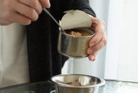 Un homme sert de la pâtée pour chiot dans une gamelle en métal