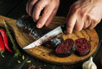 Une femme découpe un boudin noir en tranches