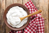 Du fromage blanc dans un bol avec une cuillère en bois