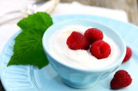 Un petit bol contenant du fromage blanc et des framboises