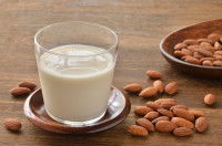 Du lait d'amande dans un verre et des amandes posées à côté