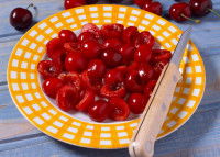 Des cerises dénoyautées avec un couteau dans une assiette