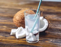 De l'eau de coco dans un verre, et une noix de coco ouverte en deux